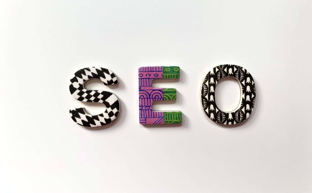 Painted three-dimensional letters that spell SEO sit on a table.