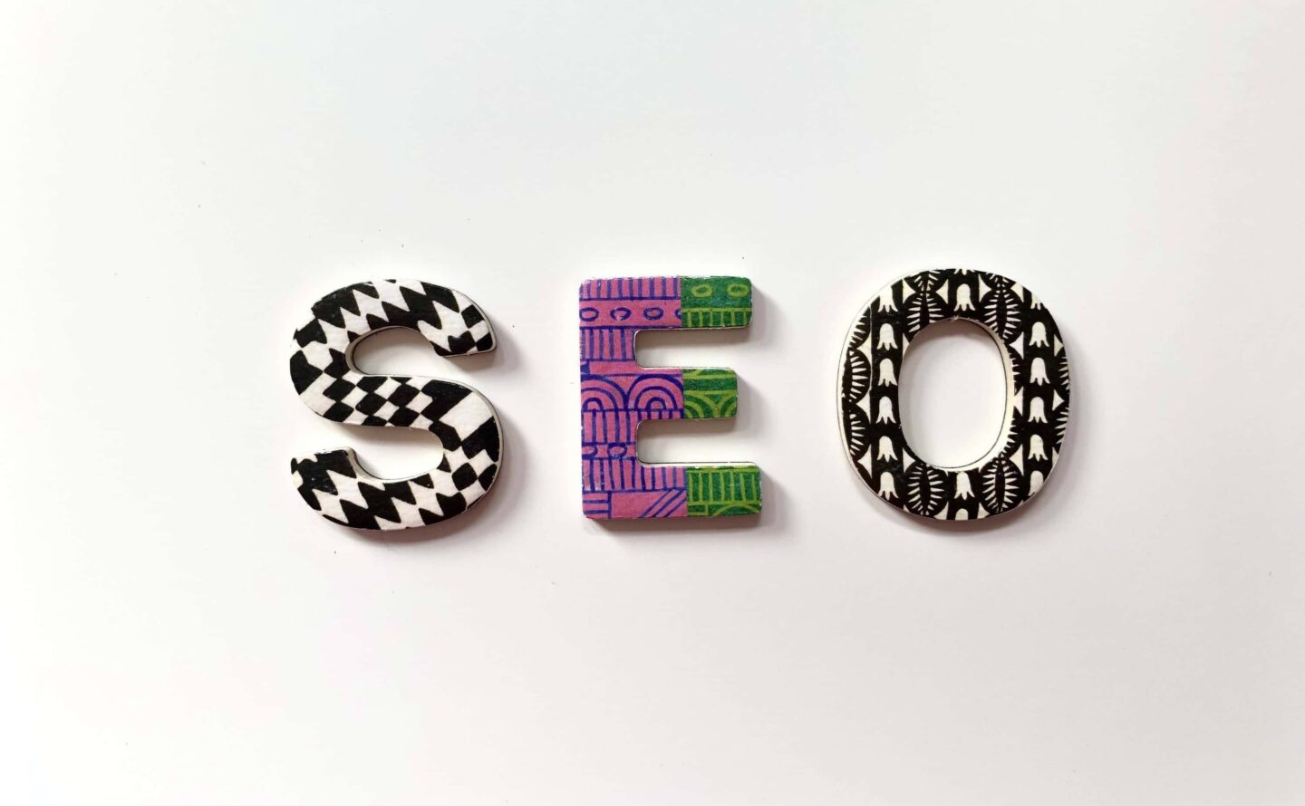Painted three-dimensional letters that spell SEO sit on a table.